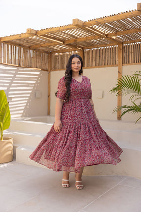 Elegant woman in floral MOTIF MAXI POLAGO PLUS dress on steps.