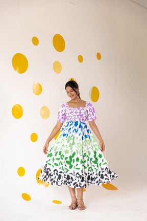 Colorful smocked maxi dress against vibrant polka dot background.