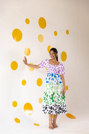 Woman wearing multicolour smocked maxi dress against playful yellow wall.