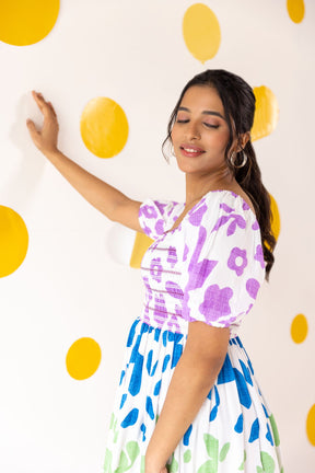 Multicolour smocked maxi dress on model against yellow polka dot background.