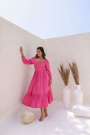 Woman in pink butta cotton maxi dress against a minimalistic background.