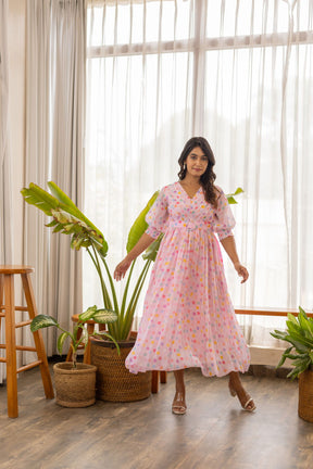 Model wearing a pink polka pleated maxi dress in a bright room.
