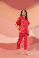 Stylish woman in pink satin co-ord outfit against soft pastel background.