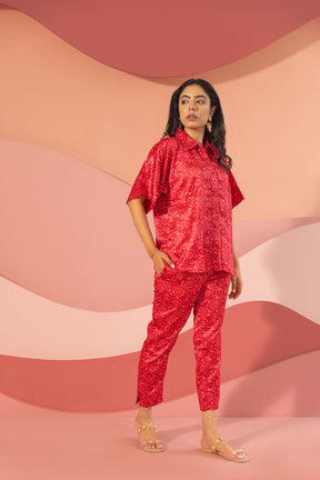 Stylish woman in pink satin co-ord outfit against soft pastel background.
