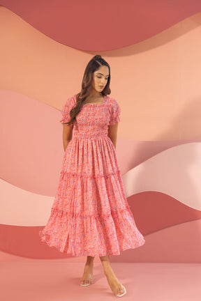 Pink smocked maxi dress displayed against a soft pastel background.