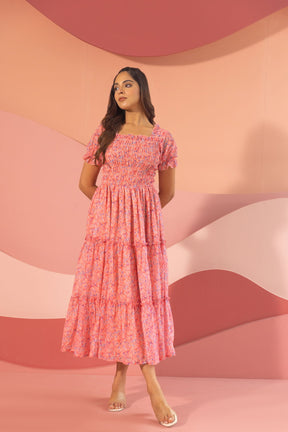 Elegant pink smocked maxi dress on a model against a colorful backdrop.