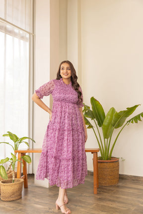 Elegant pink smocked nursing maxi dress in bright indoor setting.