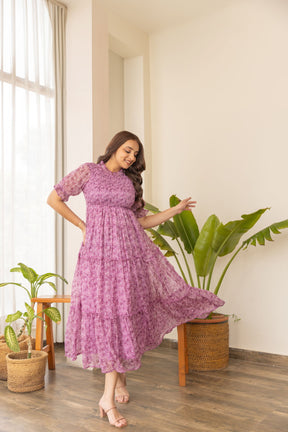 Pink smocked nursing maxi dress in a stylish indoor setting.