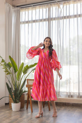 Model wearing a vibrant pink wave nursing maxi dress indoors.