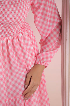Pink gingham maxi dress with smocked bodice and long sleeves.