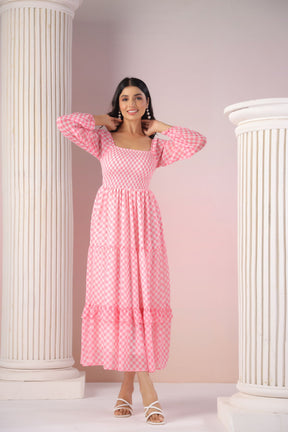 Woman in pink gingham maxi dress posing elegantly in studio.