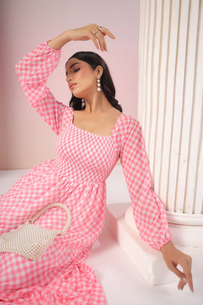 Elegant woman in pink gingham maxi dress with pearl accessories.