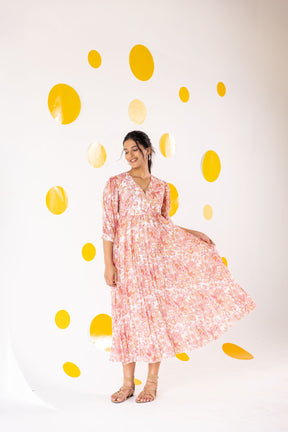 Woman wearing pleated motif maxi dress against yellow polka dot background.