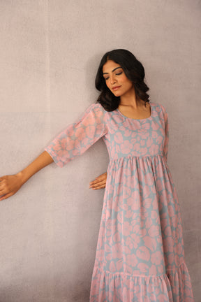 Woman modeling a grey and pink floral maxi dress against a neutral background.