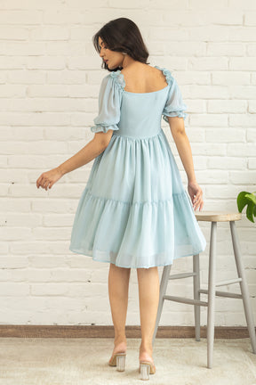 Pastel green midi dress with puff sleeves and tiered skirt.