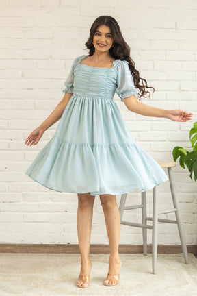 Pastel green midi dress with puff sleeves and tiered skirt.