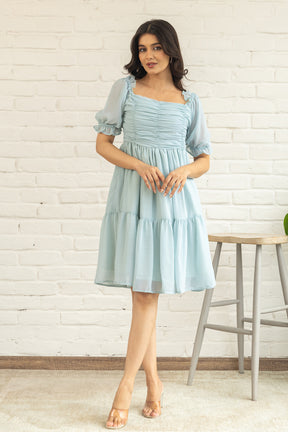 Pastel green midi dress with puff sleeves and ruffled hem.