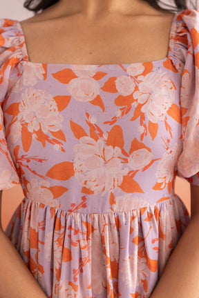 Pastel maxi dress with floral design in lavender and orange tones.