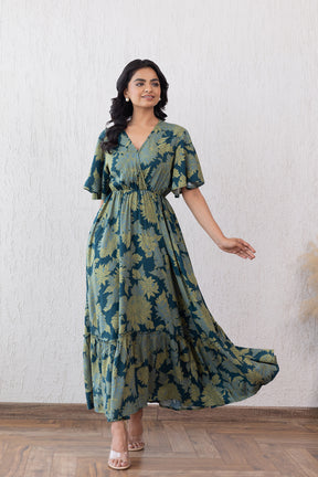 Elegant green floral maxi dress with flutter sleeves and flowing silhouette.