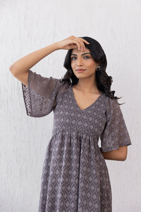Woman modeling a grey jacquard maxi dress with stylish sleeves.