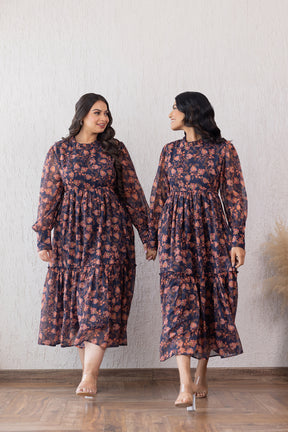 Two women wearing floral MOTIF CLOSED NECK MAXI dresses, smiling and holding hands.