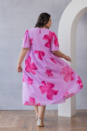 Plus-size woman wearing pink floral maxi dress by Polago Plus.
