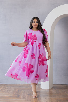 Plus-size model in pink floral maxi dress by Polago Plus.