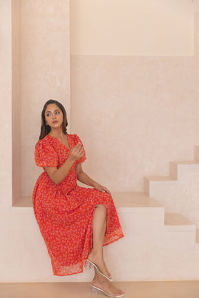 Elegant woman in red chiffon slit maxi dress on stairs.