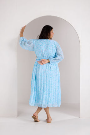 Woman in a sky blue pleated maxi dress, showcasing stylish back view.