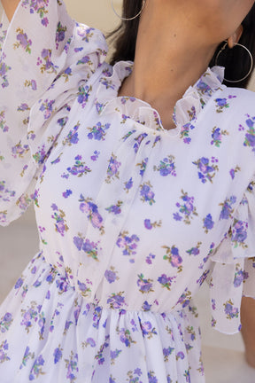 White chiffon maxi dress with floral print and ruffled sleeves.