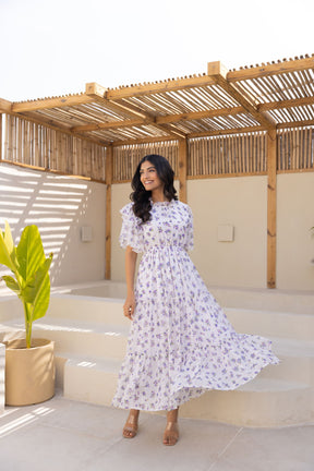 Stylish woman in white chiffon minimal maxi dress with floral pattern.