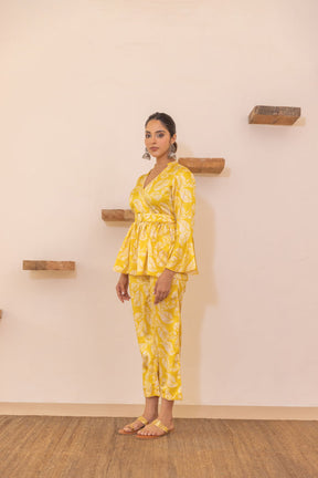 Yellow tropical satin co-ord set with floral pattern, model standing against wall.