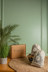 Gift box with elegant bags and greenery backdrop in soft tones.