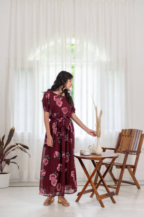 Elegant woman in wine floral dress, styled with home decor.