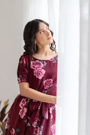 Elegant woman in wine floral co-ord near window.