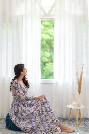 Woman in floral smocked co-ord set sitting by window.