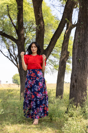 Stylish red and blue co-ord outfit in nature setting.