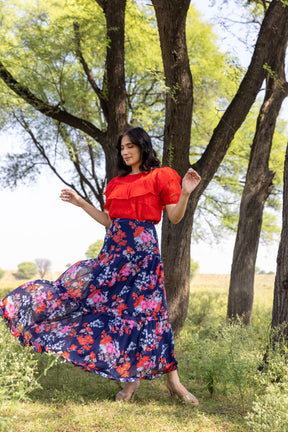 Elegant woman in red and blue floral co-ord dress outdoors.