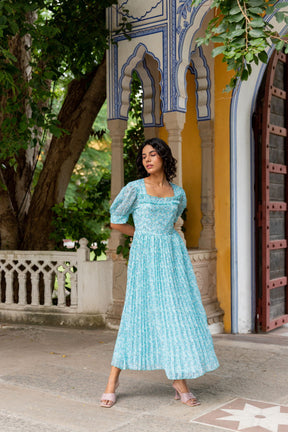 Stylish woman wearing a sky blue pleated maxi dress outdoors.