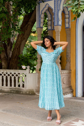 Sky blue pleated maxi dress worn in a lush outdoor setting.