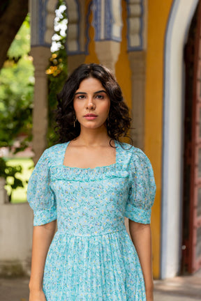 Woman wearing a sky blue pleated maxi dress outdoors.